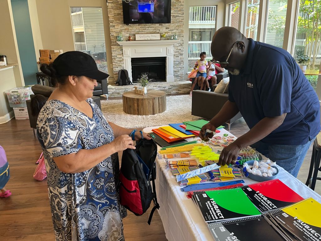 Two adults standing near school supplies