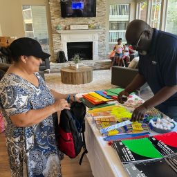 Two adults standing near school supplies