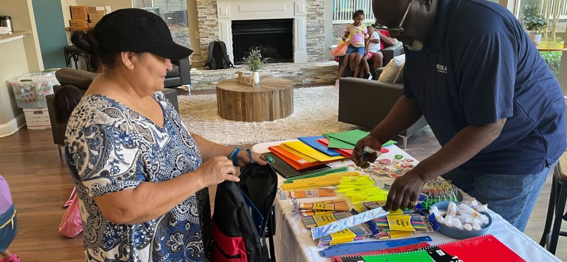 Two adults standing near school supplies