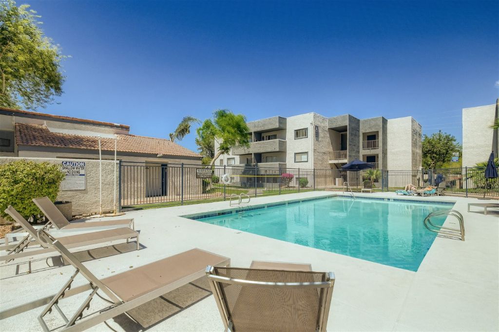 A pool with chairs and a fence