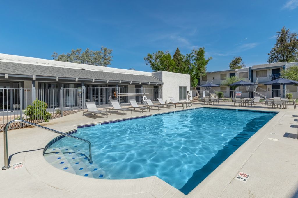 An apartment swimming pool with chairs and umbrellas